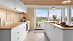 Una cocina moderna con armarios de madera, encimera de madera y un ventanal con vistas al exterior.