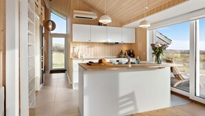 Una cocina moderna con armarios de madera, una isla central y un amplio ventanal con vistas al exterior.