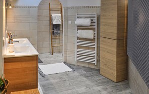 A bathroom with a wooden vanity, a sink, a towel rack, and a shower area with a ladder. - Lovely home in Aramon (Aramon)