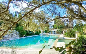 A swimming pool surrounded by lush greenery and a small building with a roof. - Lovely home in Aramon (Aramon)