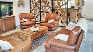 Een moderne woonkamer met leren banken, een salontafel en een televisie.