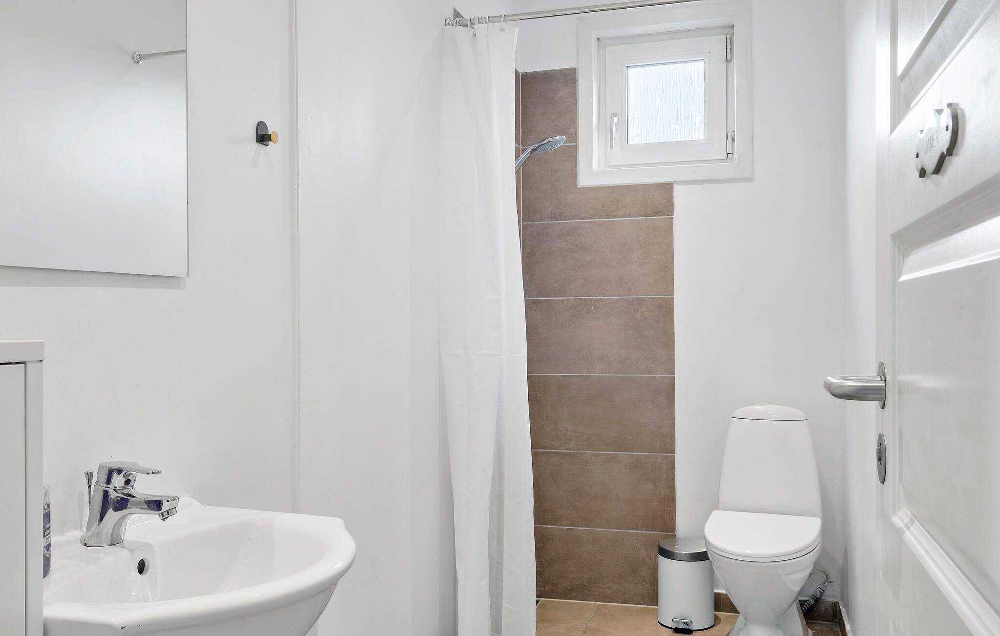 Une salle de bain avec un lavabo blanc, des toilettes et un espace douche.