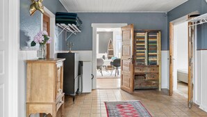 A hallway with a wooden cabinet, a glass vase with flowers, a drying rack, and a surfboard. - Amazing home in Vandel with Wi-Fi (Vandel)