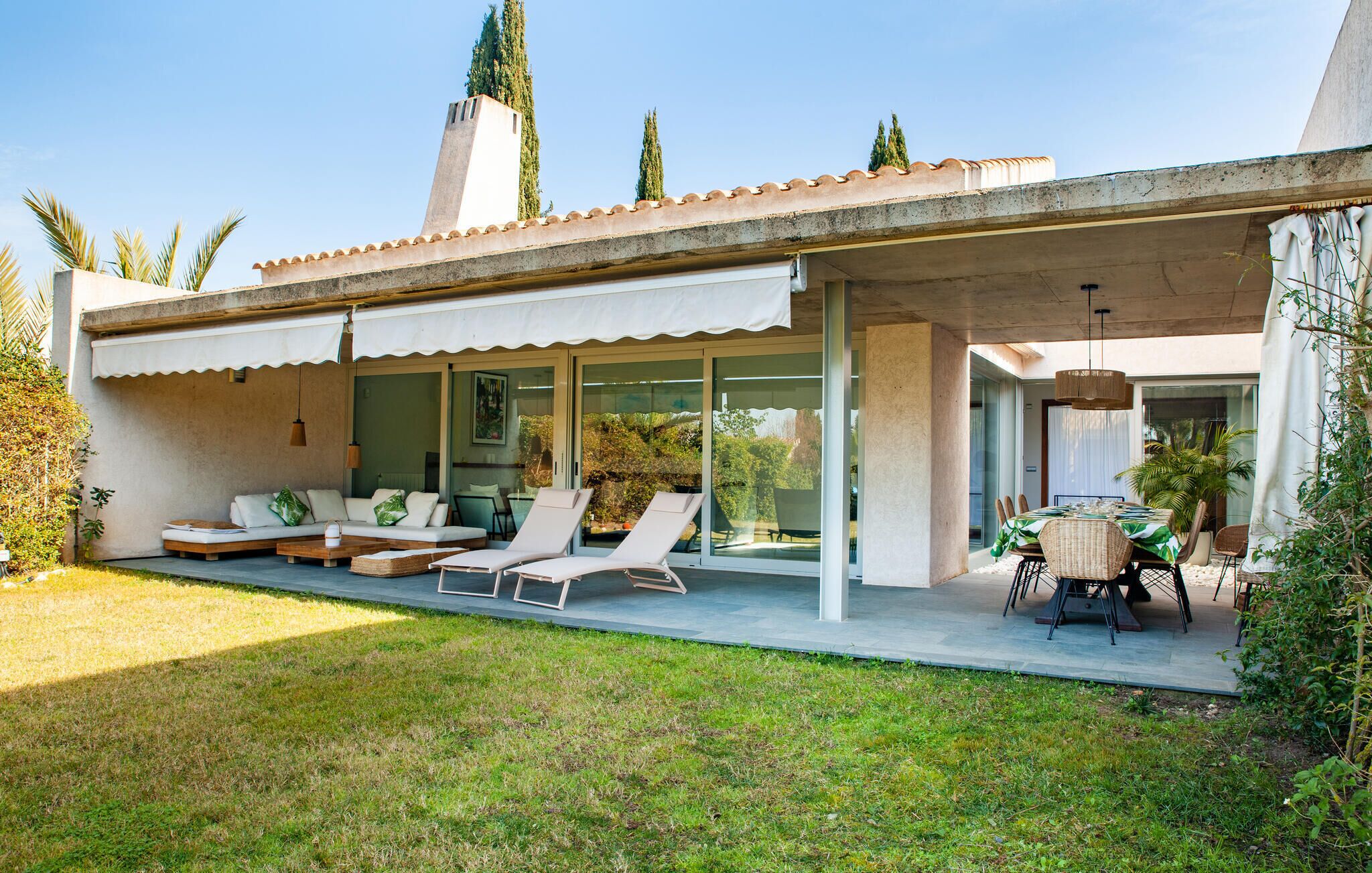 A modern house with a covered patio, outdoor seating, and a dining area.