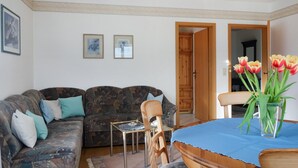 A living room with a sofa, a small table, and a chair. There are two framed pictures on the wall. - Stunning apartment in Winterberg (Winterberg)