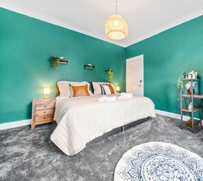 Cozy retreat with a neutral-toned bed, wooden nightstand, and comfortable desk area.