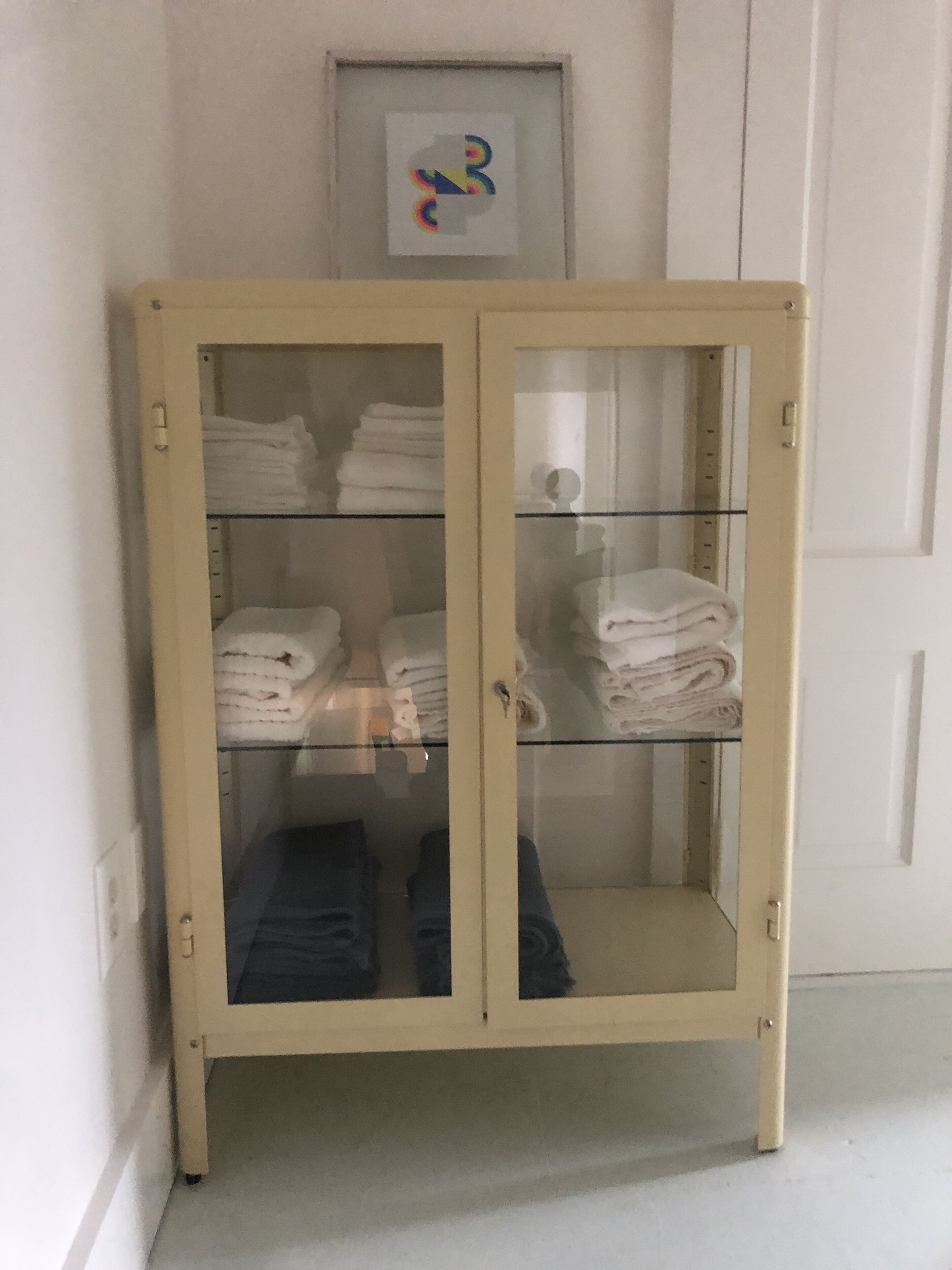 A glass-fronted cabinet with multiple shelves, each holding folded towels.