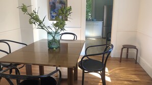 A dining area with a wooden table, black chairs, and a vase with green plants. - Sweet Cozy Victorian in Housatonic. Close to everything.  (Housatonic)