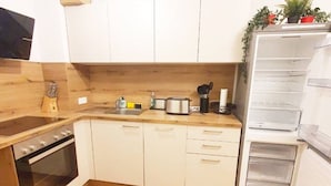 A kitchen with white cabinets, a wooden countertop, a stove, a sink, and a refrigerator. - Gemütliche Wohnung in Leipzig Zentrum mit Terrasse (Leipzig)