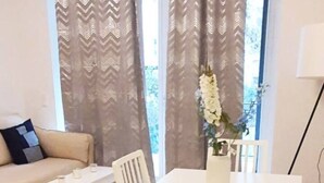 A living room with a sofa, a coffee table, and a dining table with chairs. There is a vase with flowers on the dining table. - Gemütliche Wohnung in Leipzig Zentrum mit Terrasse (Leipzig)