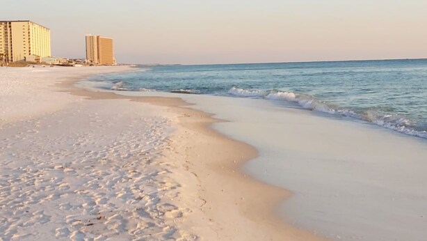 A beach with a sandy shore and ocean waves. There are buildings in the background. - BIG DISCOUNTS ON ALL MONTHLY RENTALS  - EXLARGE FACING  Emerald Coast Gulf Front (Panama City Beach)