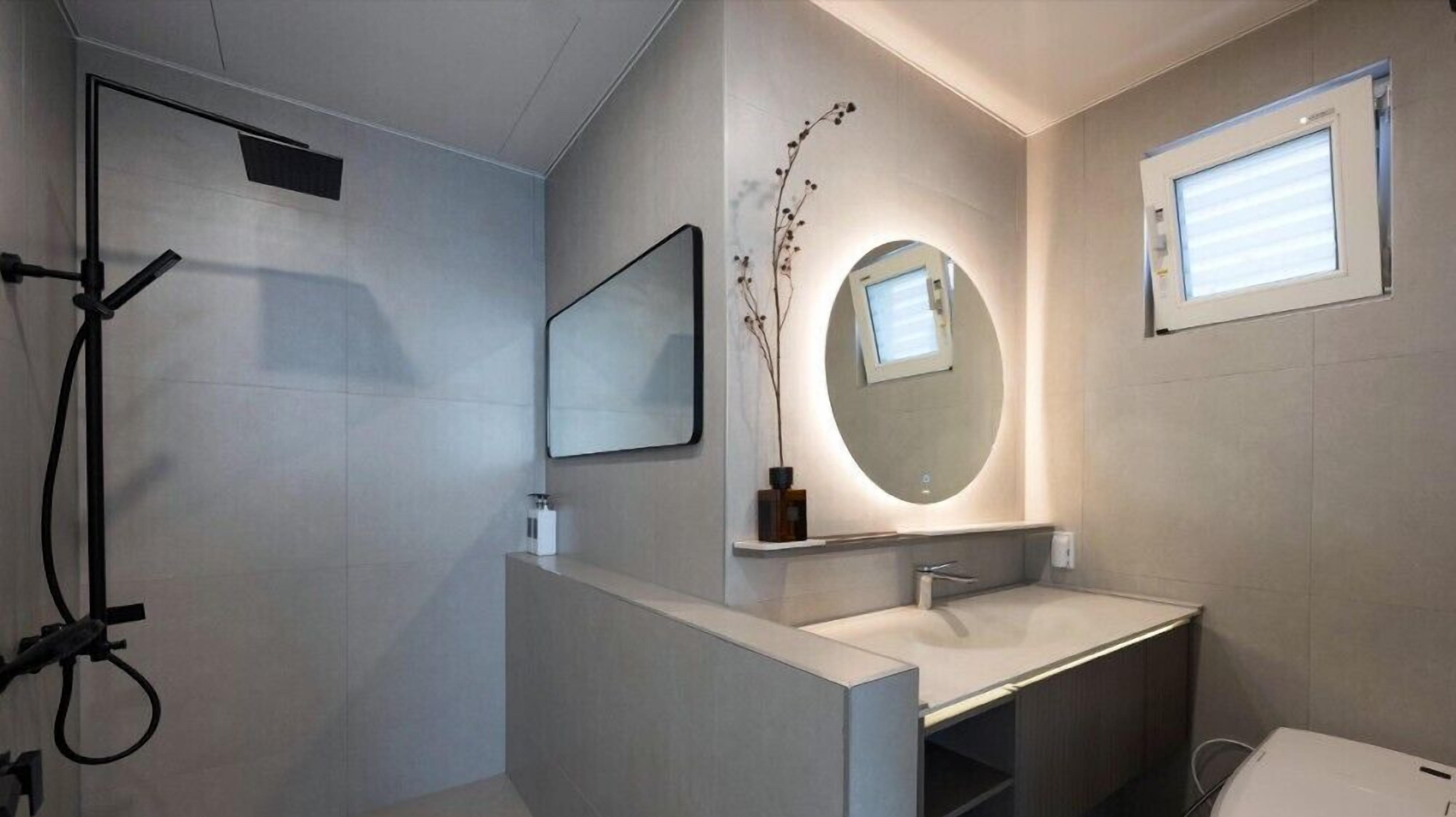 A modern bathroom with a shower, a sink, a mirror, and a window.