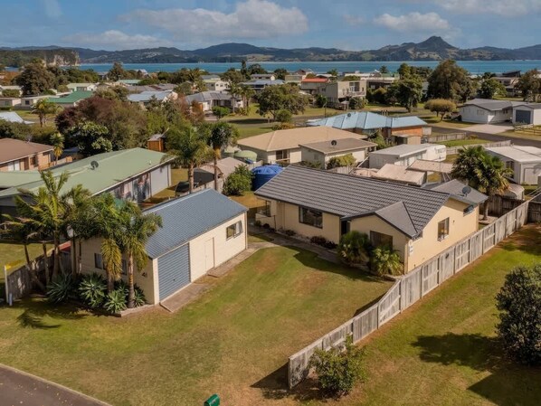 A residential area with houses, a fenced yard, and a body of water in the background.
