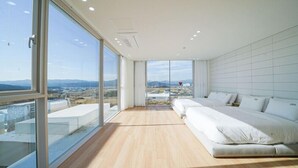 A modern bedroom with a large bed, a view of a cityscape, and a balcony. - Stay 13 Wol (Gyeongju)