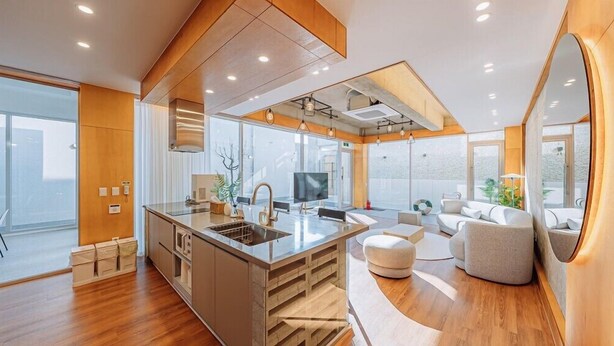 A modern kitchen with a central island, a dining area with a sofa, and a large window providing natural light. - Stay 13 Wol (Gyeongju)