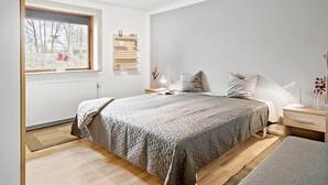 A bedroom with a large bed, bedside tables, a window with a view of trees, and a bedside lamp.