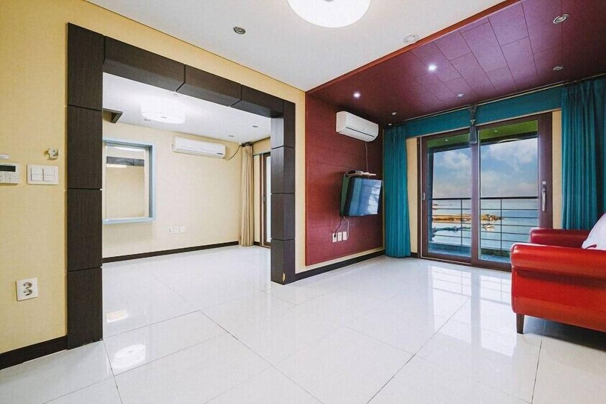 Una sala de estar moderna con un sofá rojo, un televisor en la pared y un balcón con vistas.