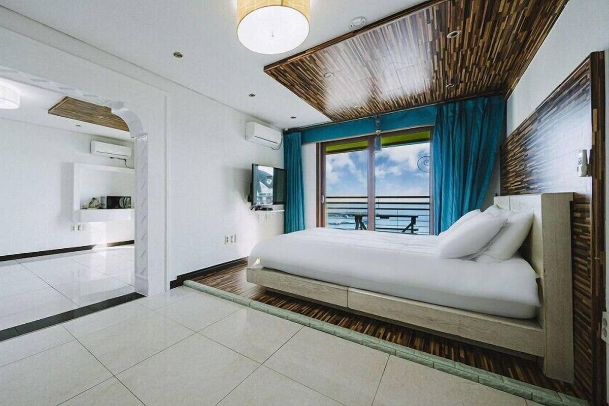 Habitación de hotel moderna con una cama grande, televisión y vistas al mar.