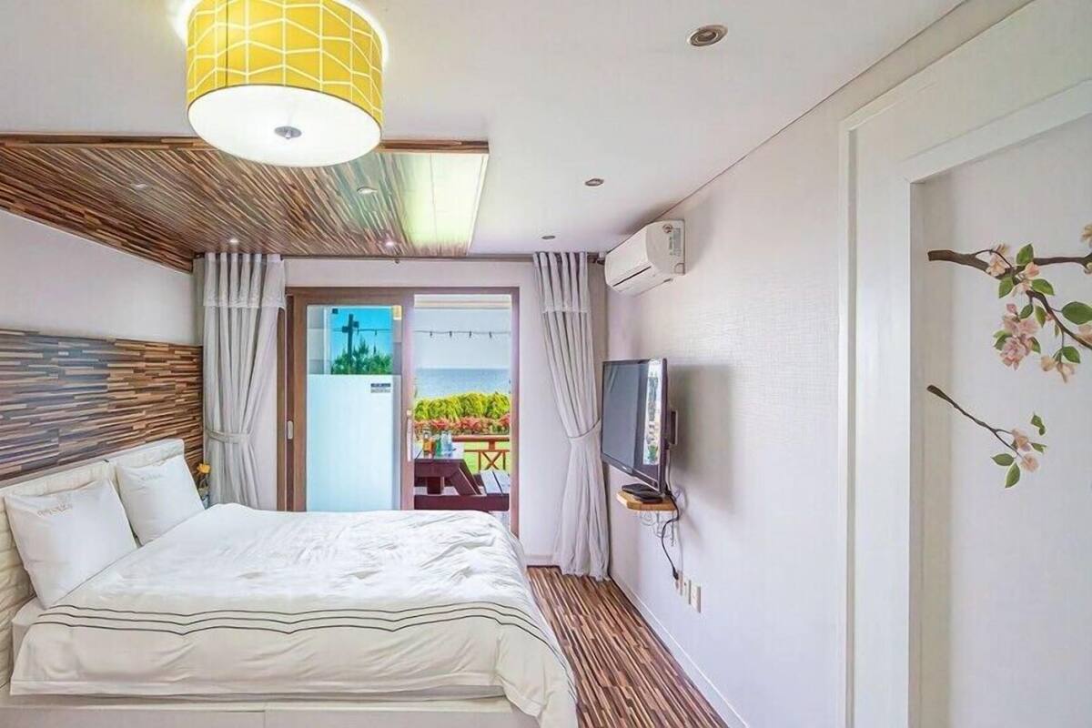 Un dormitorio con cama, televisor y vista al exterior.