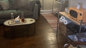 A living room with a sofa, coffee table, and a microwave on a shelf. - Springer Station (Springer)