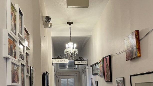 A hallway with a chandelier, framed pictures on the walls, and a door labeled "Full Bath" and "Half Bath". - Springer Station (Springer)