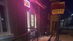 A building with a 'OPEN' sign, a staircase with metal railings, and a flag outside. - Springer Station (Springer)