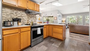 A modern kitchen with wooden cabinets, a stainless steel stove, and a large island. - Stunning views, Strong Wi-fi, and Private Beach! (Lilliwaup)