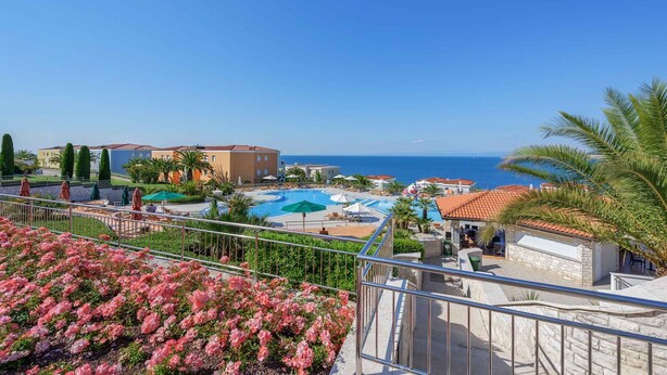 A resort with a swimming pool, palm trees, and a view of the sea. - Holiday apartment with air conditioning, internet and private parking space (Savudrija)