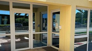 A building entrance with glass doors and a yellow exterior wall. - Holiday apartment with air conditioning, internet and private parking space (Savudrija)