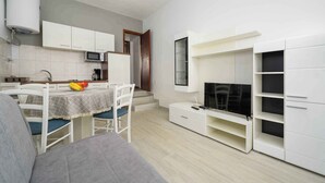 A modern kitchen with white cabinets, a microwave, and a dining area with a table and chairs. - Holiday apartment for 2 people on the ground floor (Umag)