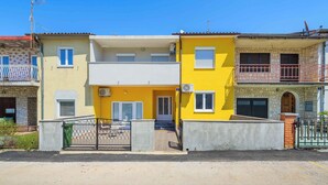 A row of two-story residential buildings with balconies, a gated entrance, and a clear sky. - Holiday apartment for 2 people on the ground floor (Umag)