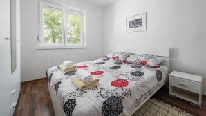 A bedroom with a bed, a bedside table, a window, and a framed picture on the wall. - Holiday apartment for 2 people on the ground floor (Umag)