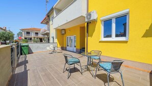 A yellow building with a balcony, outdoor furniture, and a stop sign. - Holiday apartment for 2 people on the ground floor (Umag)