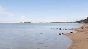 A beach with calm water, a sandy shore, and a distant island. - Cozy home in Vordingborg with WiFi (Vordingborg)