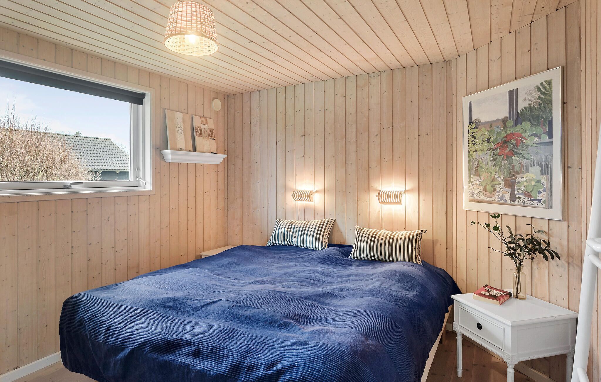 Quarto com uma cama grande, paredes de madeira, uma janela e um quadro.