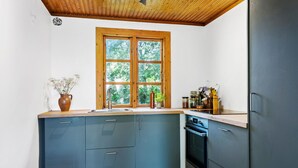 Une cuisine compacte avec une fenêtre en bois, des placards intégrés et une cuisinière.