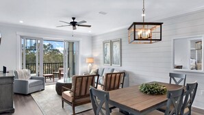 A spacious dining area with a wooden table and chairs, a ceiling fan, and a hanging light fixture.