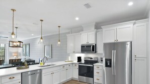 A modern kitchen with white cabinetry, stainless steel appliances, and pendant lighting.