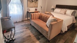 Een hotelkamer met een bank, een bed, een plafondventilator, een salontafel en een schilderij aan de muur.