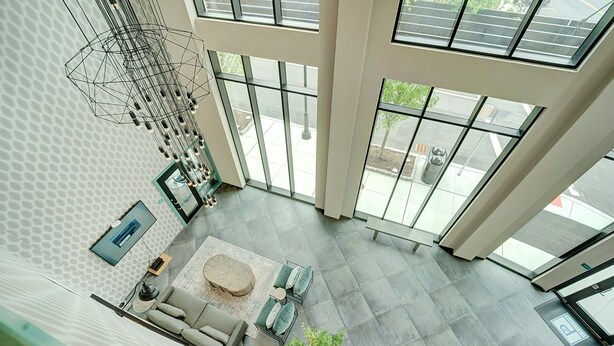 A spacious atrium with high ceilings, large windows, a modern geometric light fixture, and a seating area with a sofa and a round table. - 2 King Bed 2 Bath Easy ride to NYC and Shopping (Hackensack)