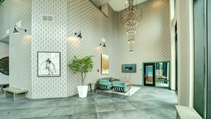 A spacious lobby with a patterned wall, a large potted plant, a seating area with chairs, a television, and a staircase. - 2 King Bed 2 Bath Easy ride to NYC and Shopping (Hackensack)