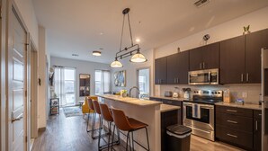 A modern kitchen with dark cabinets, stainless steel appliances, and a central island with bar stools. - 2 King Bed 2 Bath Easy ride to NYC and Shopping (Hackensack)