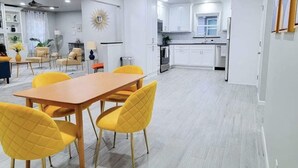A modern kitchen with white cabinets, a dining area with a wooden table and yellow chairs, and a ceiling fan. - Hot Tub- Rose District-Walk to Shopping & Dining (Broken Arrow)