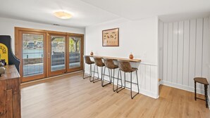 Een moderne keuken met een houten aanrecht, vier barkrukken en een groot raam met uitzicht.