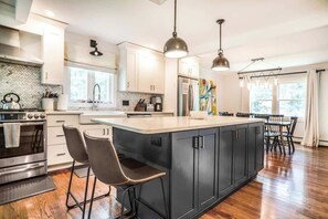 A modern kitchen with a large island, stainless steel appliances, and pendant lighting. - Woodstock Family Home w/ Tree House + Heated Pool (Woodstock)