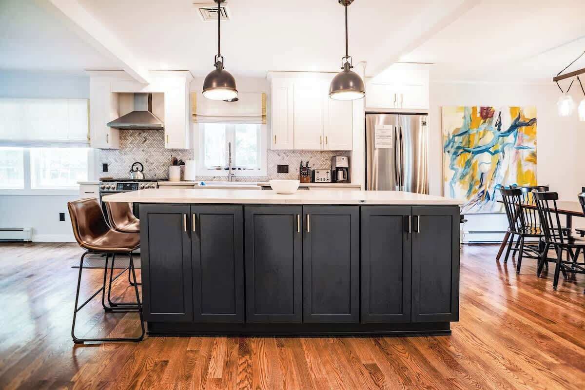 A modern kitchen with a large island, stainless steel appliances, and pendant lighting.