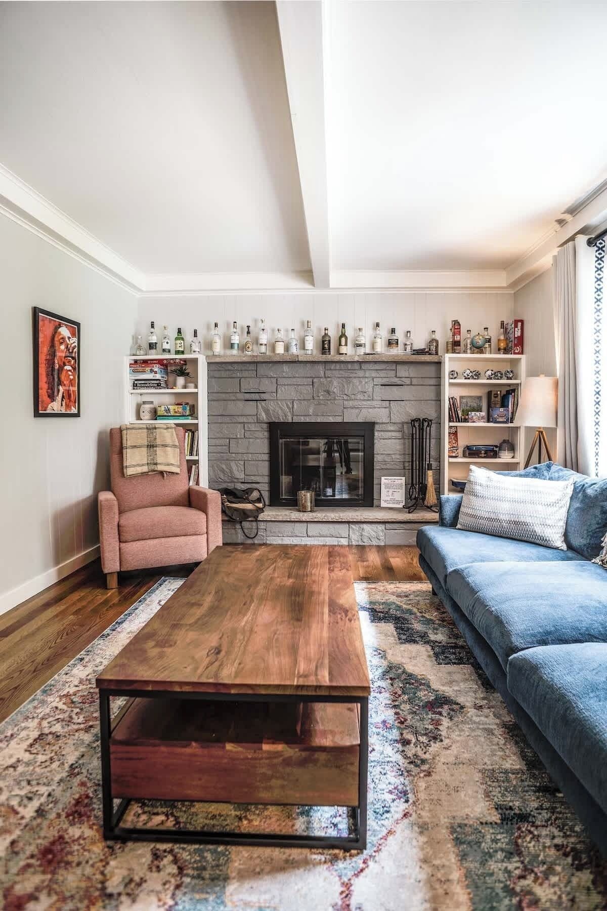 A living room with a fireplace, a sofa, a coffee table, and a bookshelf.