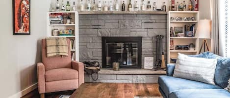 A living room with a fireplace, a sofa, a coffee table, and a bookshelf.