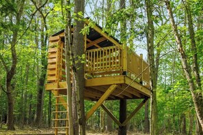 A wooden treehouse with a ladder, surrounded by a forest. - Woodstock Family Home w/ Tree House + Heated Pool (Woodstock)