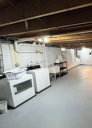 A basement with a washing machine, a dryer, and a small table. - Woodstock Family Home w/ Tree House + Heated Pool (Woodstock)